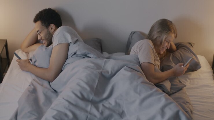 Couple in bed using phones