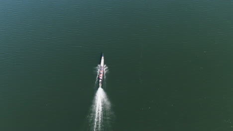 Drone-tilt-follow-shot-of-a-traditional-long-boat-on-Moebyel-Lake-in-Myanmar