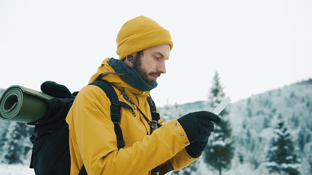 Escursionista che utilizza un tablet in un paesaggio invernale