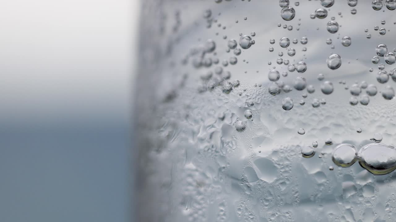 Macro view of bubbles rising in a clear liquid, showcasing effervescence with a shallow depth of field and soft lighting