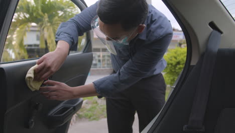 man with face mask wiping off and disinfecting his car after dropping off his passengers during covid-19 pandemic