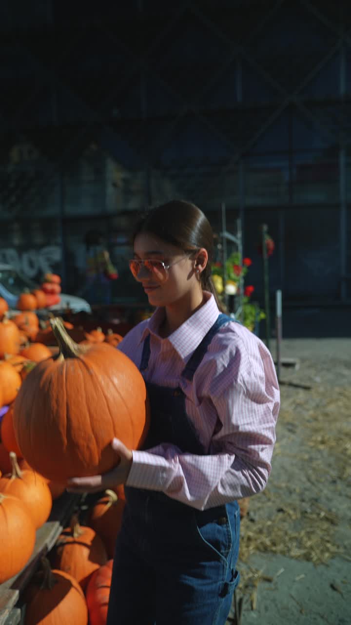 가을 시장에서 큰 호박을 들고 있는 십대.