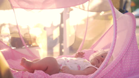 baby lying in pink bassinet outdoor