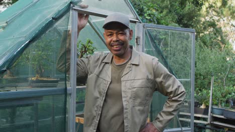 African-american-male-gardener-looking-at-camera-and-smiling-at-garden-center