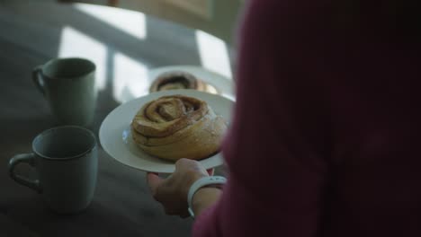 Cinnamon-swirl-on-a-plate-in-persons-hand,-mid-shot