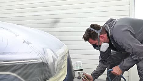 man spray painting front and side of vehicle with varnish