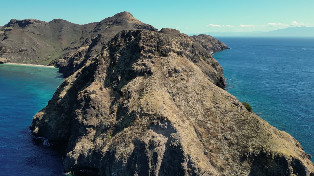 Orbita di drone attorno al bordo di un promontorio arido e brullo che rivela una baia protetta