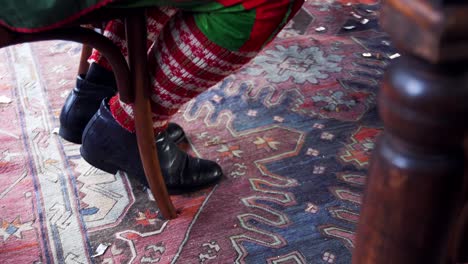 funny legs dancing under the table. male's legs in colorful fairy clothing and old black shoes tapping on the floor