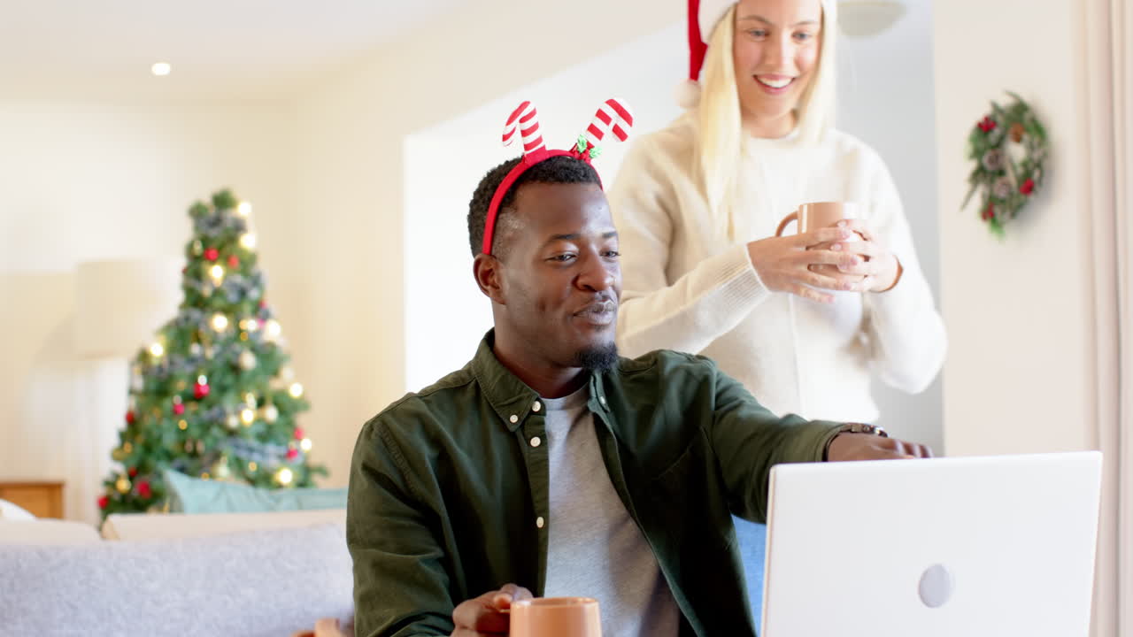 diverse couple enjoying holiday video call at home with Christmas decorations