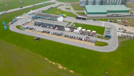 aerial drone footage orbiting and spinning around a large gas station with a restaurant in the middle of green grassy fields in estonia. place is called tikupoiss and is besides tartu highway at day.