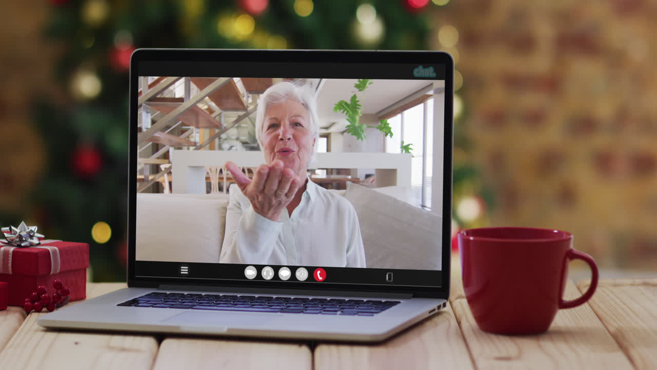 feliz mujer mayor caucásica en videollamada en computadora portátil, con decoraciones de navidad y árbol