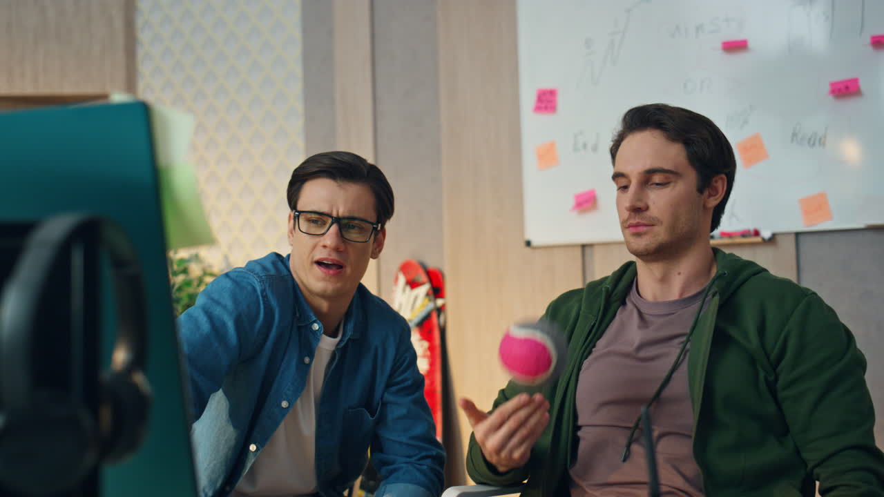 창의적인 동료들이 사무실에서 컴퓨터를 사용하고, 편안한 사업가가 공을 치고 있다.