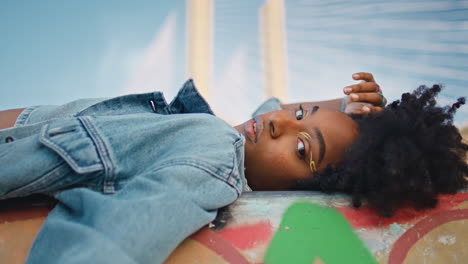 stylish model posing lying outdoors in jeans jacket close up. girl relaxing