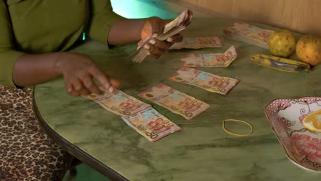 slow motion black female african woman organised paper bills money ghanaian cedi currency of ghana in a table in her house for paying taxes to government