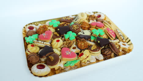 hand taking christmas cookies, which is laid on a gold plate decorated and stacked wearing different colors of species and sizes in the normal speed motion capture at 24fps