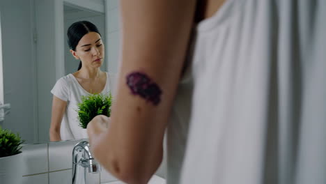 woman looking at injury on her arm in a bathroom