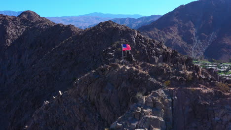 an american flag blowing in the wind on top of a large mountain