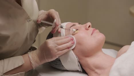 un paciente se reclina mientras recibe una inyección facial de un clínico en un entorno de spa médico, destacando el tratamiento estético sin centrarse en marcas específicas