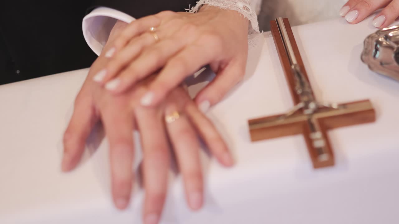 Bride and groom holding hands near cross, symbolizing unity and faith