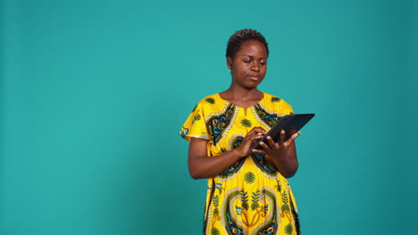 Smiling-happy-person-checking-internet-websites-on-her-tablet-in-studio