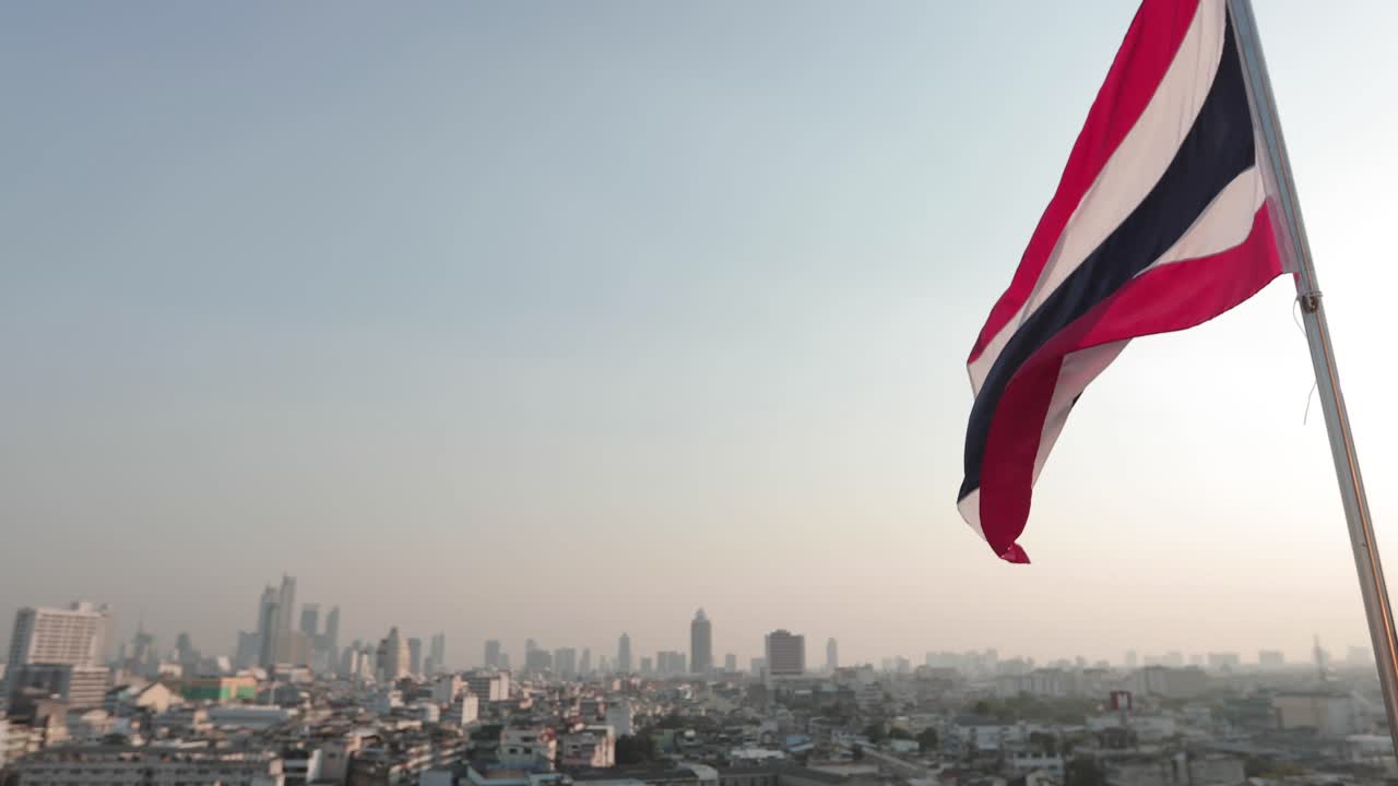 Bandiera della Thailandia sventolante con vista su Bangkok al tramonto, filmato 4K.