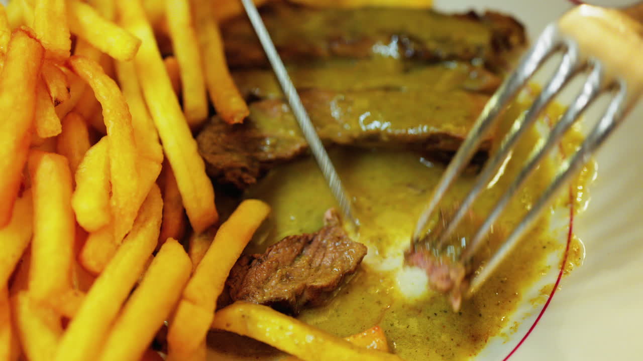 Close up of a plate of fries with meat and green sauce on a plate