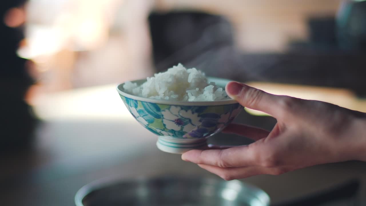 mano sosteniendo un tazón floral japonés de un arroz caliente humeante