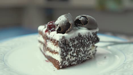 una apetitosa rebanada de pastel de chocolate y crema gira en un plato con cerezas