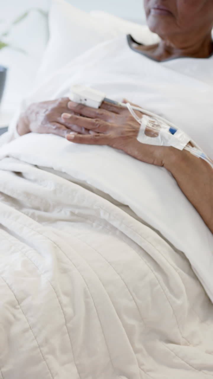 Vertical video of senior african american woman hand with intravenous, slow motion, copy space