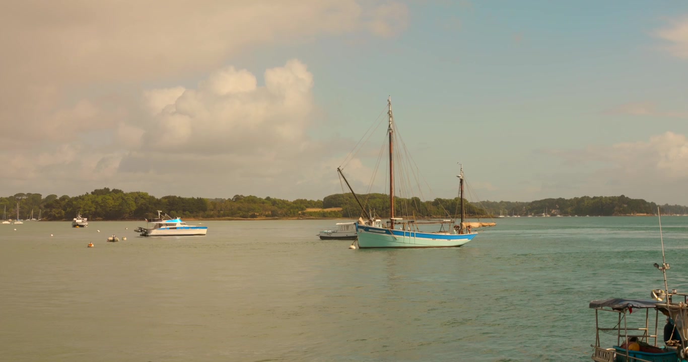 Barca a vela ancorata su acqua calma con una costa distante nel Golfo di Morbihan, Francia