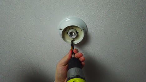 desenroscar con un taladro una lámpara vieja y quitarla del techo.