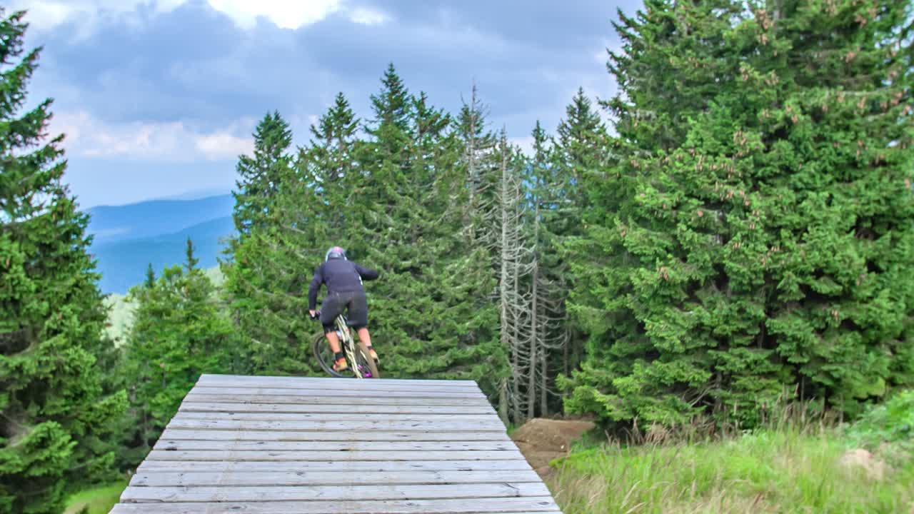 내리막 서킷의 나무 경사로에서 점프하는 산악 자전거 타는 사람