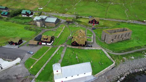 aerial pan of st olav church and st magnus cathedral ruins near turf roof houses, kirkjubour