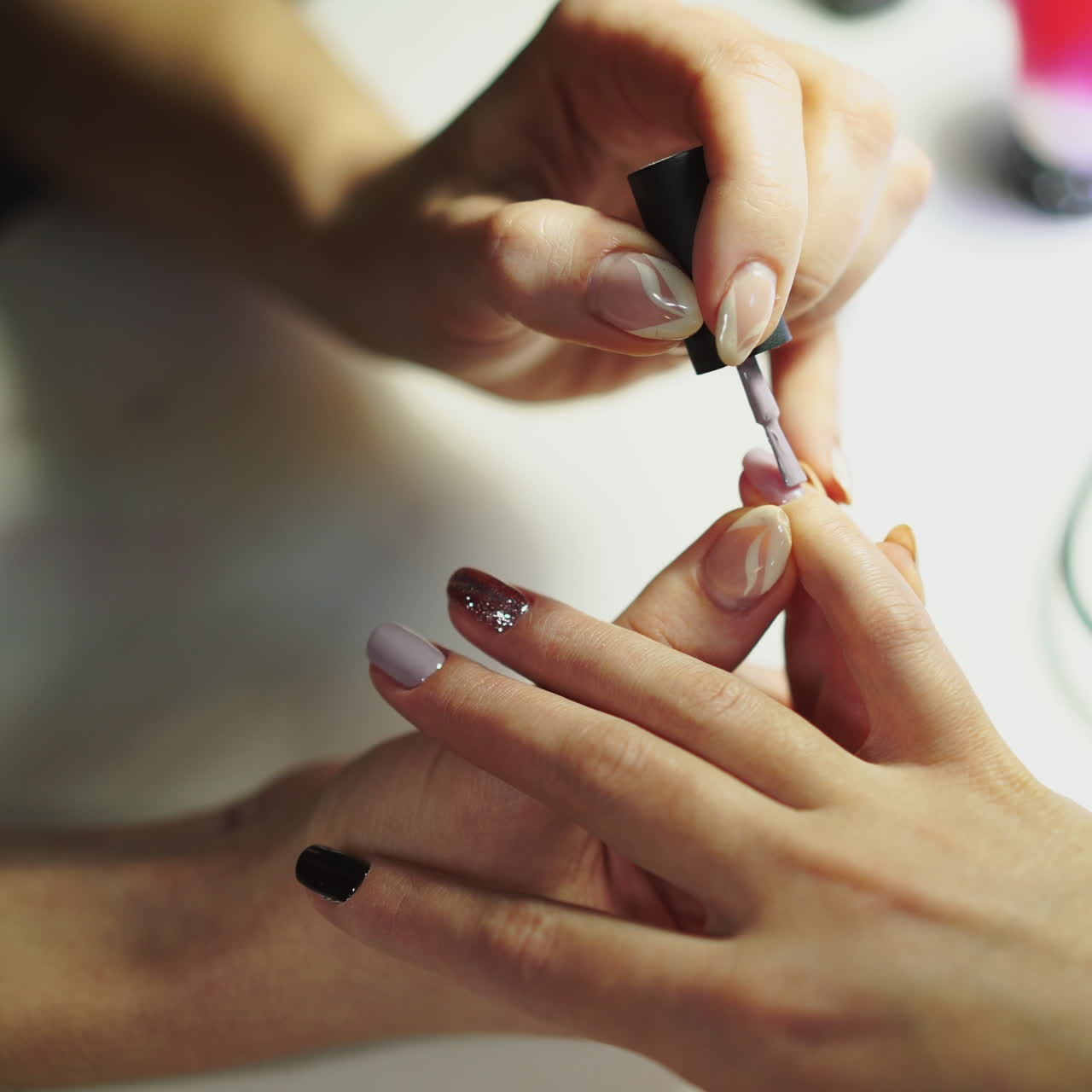 Close-up of female hands making manicure with nail lacquer in beauty salon. Woman hands receiving a manicure by a beautician. Woman is getting nail manicure, spa treatments