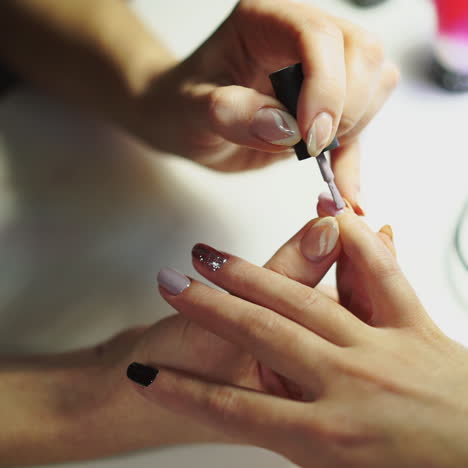 close-up of female hands making manicure with nail lacquer in beauty salon. woman hands receiving a manicure by a beautician. woman is getting nail manicure, spa treatments