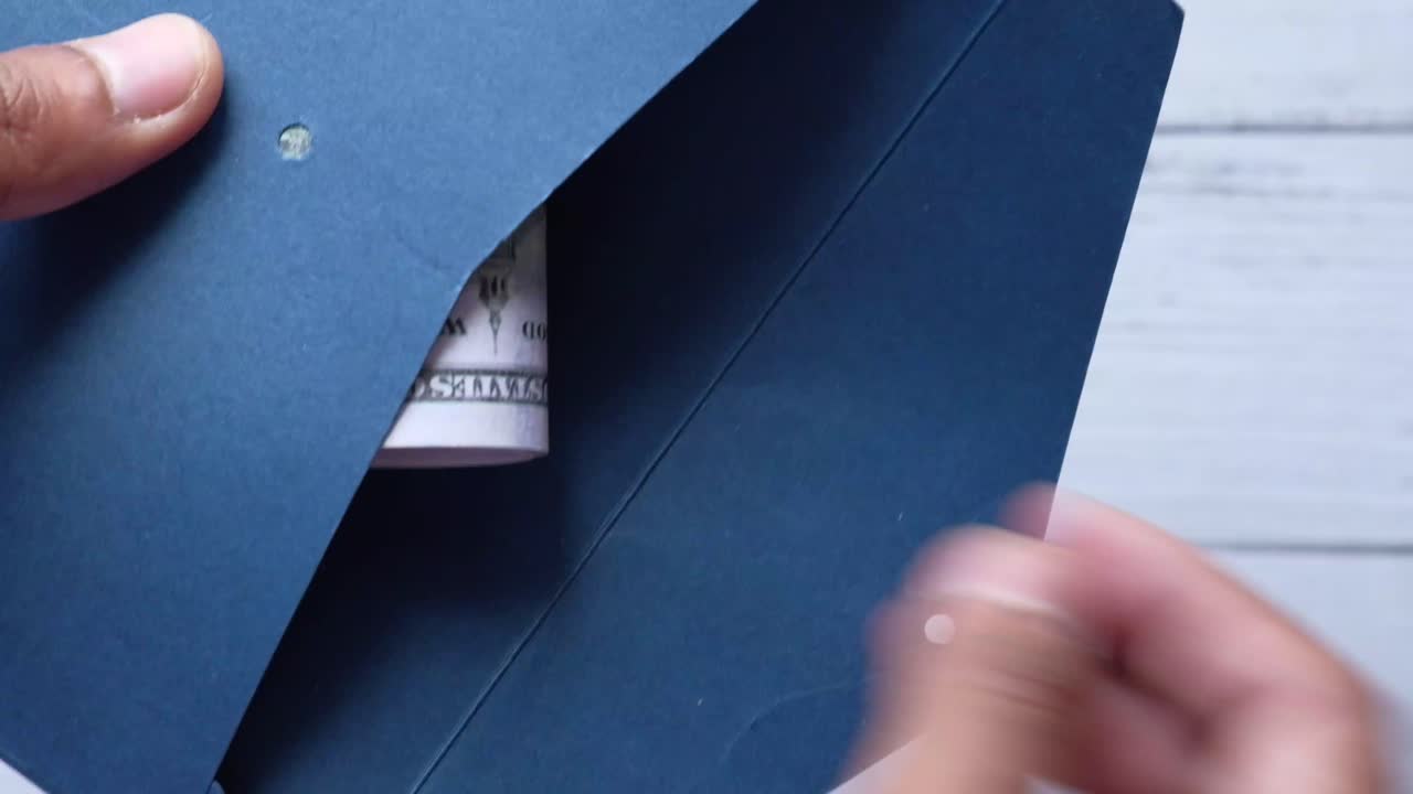 mano sosteniendo un sobre con dólares enrollados