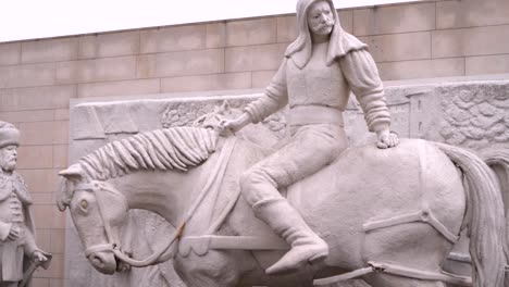 Man-on-horse-pulls-other-man-on-the-ground-"Szentvér-monda"-statue-at-Nyírbator,-Hungary,-Recorded-with-a-sony-alpha-A7-III-in-4K