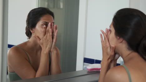 woman applying face cream in front of mirror