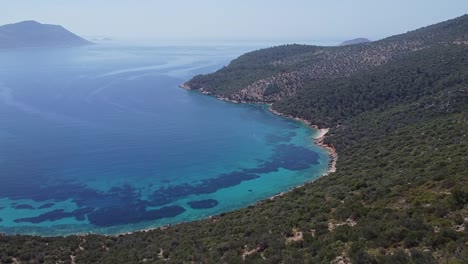 Vista-Aérea-De-La-Playa-Paradisíaca-De-Firnaz-Koyu-Con-Aguas-Azules-Del-Mar-Mediterráneo-Y-Montañas,-Pavo