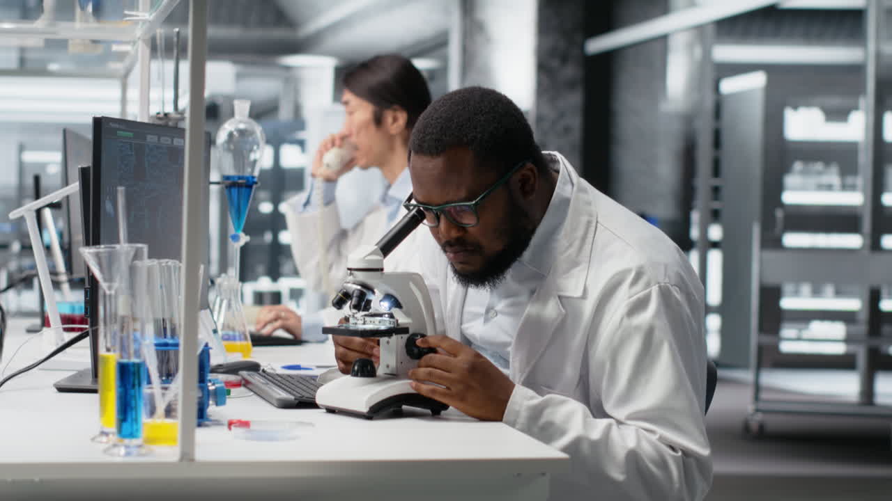 Vertical video Lab microbiologist using microscope for cellular analysis, writing information