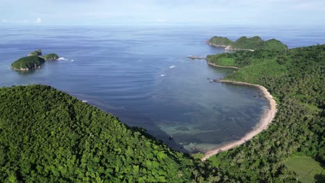 stunning high angle aerial view of turquoise bay by island with hills covered in palm trees