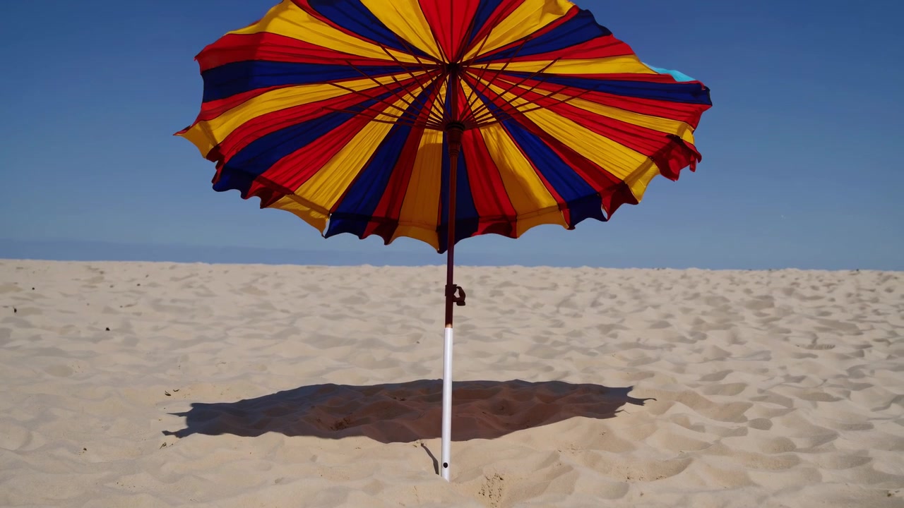 Un ombrellone colorato si apre su una spiaggia sabbiosa e soleggiata