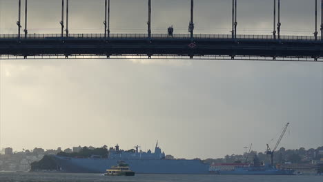 A-large-naval-ship-on-Sydney-harbour-framed-beneath-the-bridge,-Australia