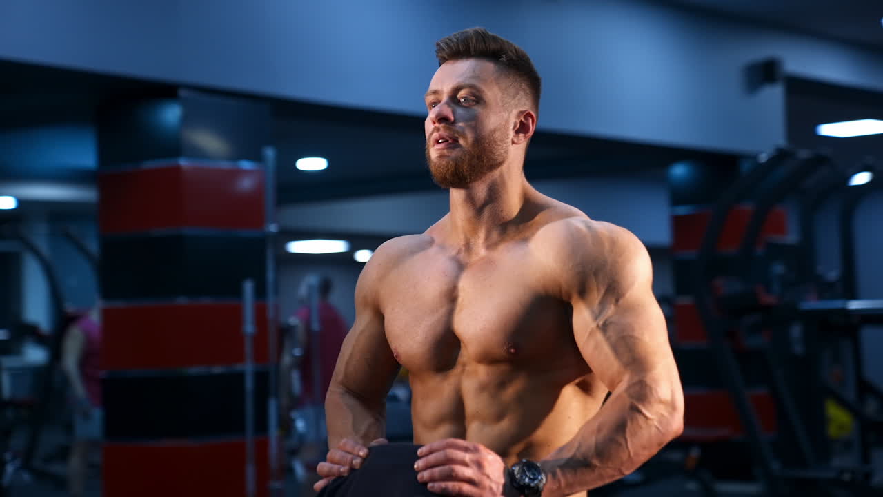 Circle view on handsome male bodybuilder with strong body and perfect abs. Male with naked torso. Slow motion.