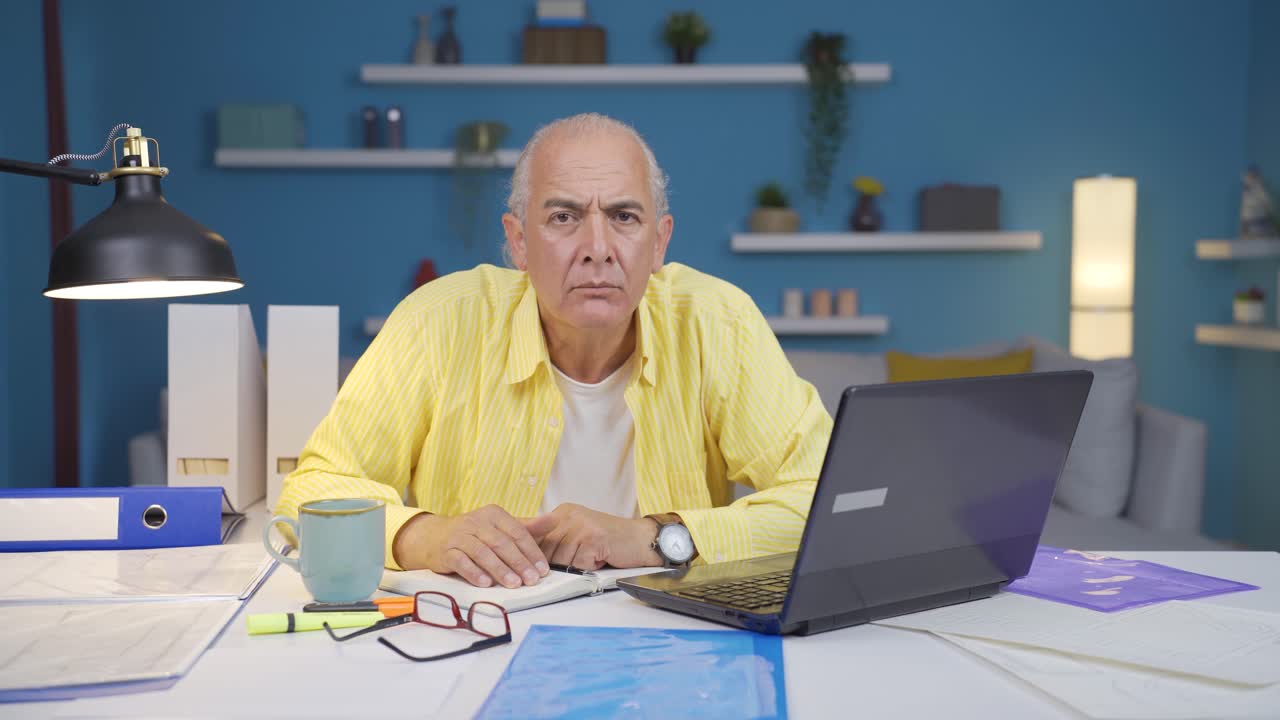 Home office worker old man looking at camera curious and confused.