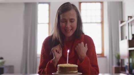 happy woman blowing candle on the cake alone at home