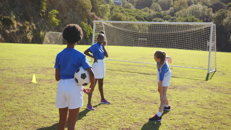 playing soccer, three school girls in uniform standing on field with ball