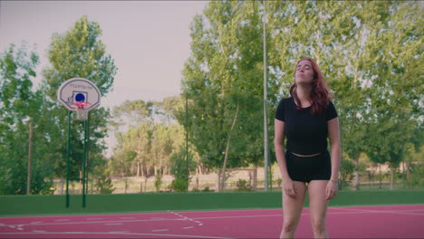 basketball court sitting redhead girl gets up and faces the camera