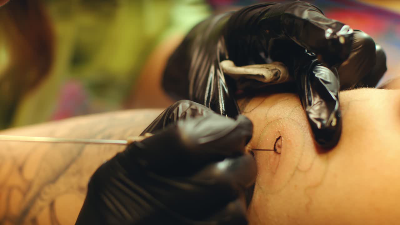 Hands of Tattoo Artist Injecting Ink into Skin of Client with Needle