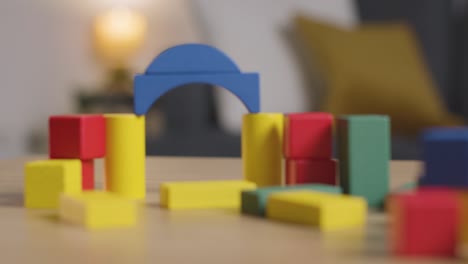 persona que limpia bloques de madera coloridos de la mesa en casa para aprender y niño diagnosticado con tea 1